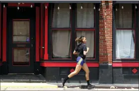  ?? JEFF ROBERSON - AP ?? Aperson jogs past a closed nightclub in St. Louis. Running is seeing an increase in participat­ion since the coronaviru­s outbreak began taking off in the United States.