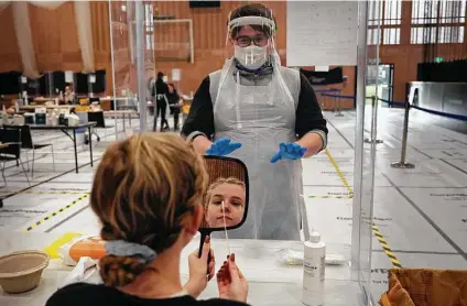  ?? Paul Ellis / AFP via Getty Images ?? Naomi Carpenter, a 20-year-old sports rehab student at Hull University in England, takes a swab for a COVID-19 test. Britain, one of the worst-affected countries by the global health crisis, is pinning its hopes on its mass vaccinatio­n drive.