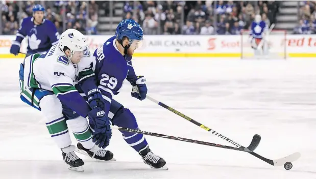  ?? — THE CANADIAN PRESS ?? Maple Leafs winger William Nylander and Vancouver defenceman Ben Hutton battle for the puck during the first period of their game in Toronto Saturday night. The Canucks couldn’t find the net, dropping a 5-0 decision to the impressive Maple Leafs.