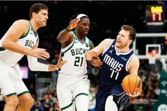  ?? — AFP file photo ?? Doncic (right) of the Dallas Mavericks goes to the basket against Jrue Holiday (centre) and Brook Lopez of the Milwaukee Bucks during the second half of a game at Fiserv Forum in Milwaukee, Wisconsin.