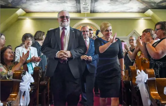  ?? Christian Snyder/Post-Gazette photos ?? Edward Pazo, left, the national president of the Croatian Fraternal Union of America, enters the sanctuary with Croatian President Kolinda Grabar-Kitarovic, right, for Mass on Sunday at St. Nicholas Catholic Church in Millvale.