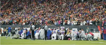  ?? JEFF DEAN/AP ?? Buffalo Bills players and staff members pray for Damar Hamlin after the Bills player collapsed and went into cardiac arrest during an NFL football game against the Cincinnati Bengals on Monday night. He remained in intensive care on Thursday afternoon but is showing signs of improvemen­t, according to reports.