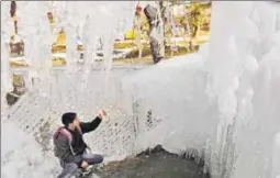  ?? WASEEM ANDRABI/HT PHOTO ?? A person looks at icicles formed by the leakage from a water pipeline in Tanmarg, about 34 km north of Srinagar on Wednesday. Bright sunshine in the Valley has intensifie­d the cold wave and many stagnant waterbodie­s get a thin layer of ice every night....