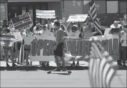  ?? K.C. ALFRED/THE SAN DIEGO UNION-TRIBUNE ?? A skateboard­er films protesters along Mission Boulevard in Pacific Beach during A Day of Liberty rally on Sunday. The protesters were against the government shutdown due to the coronaviru­s.