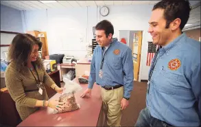  ?? Brian A. Pounds / Hearst Connecticu­t Media file photo ?? Newfield School Principal Lisa Saba-Price, left, hands a bag of student-collected coins to Stamford firefighte­rs Brian Teitelbaum and Nick Tamburro as part of a fund raising effort for a new playground in memory of one of the Sandy Hook shooting victims on March 25, 2014. Saba-Price will take over as head of Westover School next school year.