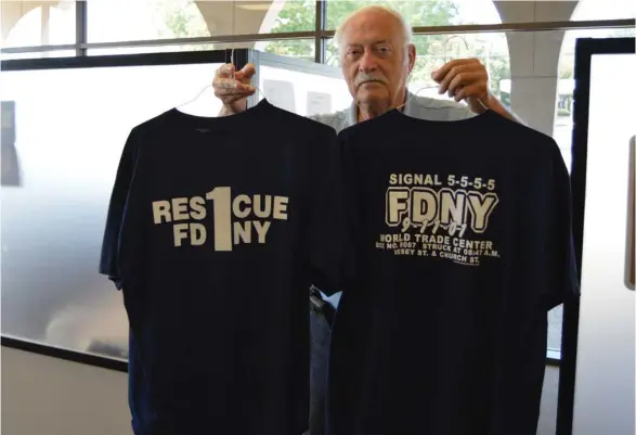  ?? (Photo by Sarah Raines, SDN) ?? Oktibbeha County Fire Services Coordinato­r Kirk Rosenhan shows off two T-shirts commemorat­ing the New York City firefighte­rs on duty during the terrorist attacks on Sept. 11.