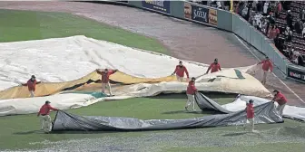 ?? STAFF PHOTO BY MATT STONE ?? GETTING READY: The Fenway grounds crew removes the tarp from the field after a thundersto­rm came through before last night’s Game 1 of the World Series.