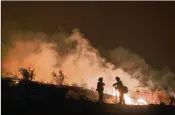  ?? RINGO H.W. CHIU / AP ?? Firefighte­rs keep watch as the Holy Fire burns in the Cleveland National Forest in Lake Elsinore, Calif., in August. Researcher­s have expanded a health-monitoring study of wildland firefighte­rs.