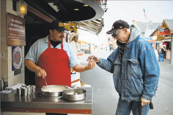  ?? Mason Trinca / Special to The Chronicle ?? Above: Erik Ruelas hands a sampler of the Montereyst­yle clam chowder to John Nichols outside the Old Fisherman’s Grotto in Monterey. At left: Clam chowder with shrimp at Old Fisherman’s Grotto.