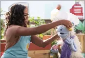  ?? ADAM ROSE — NETFLIX ?? Former first lady Michelle Obama puts a chef’s hat on Waffles, a furry puppet with waffle ears and holding Mochi, a pink round puppet, on the set of the children’s series “Waffles + Mochi.”