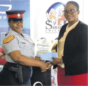  ?? ?? Woman Sergeant Allison Holness, who is a supervisor at the Whithorn Police Station, being presented with her gift from Sarah’s Children director, Sonia Clarke-bowen. She was among the top six finalists for Lasco/jcf Top Cop 2023.