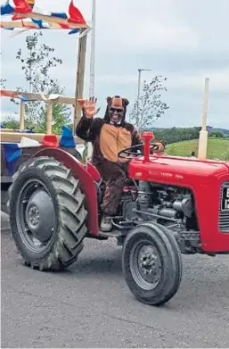  ??  ?? Duncan Collier dressed in a bear suit on his vintage tractor.