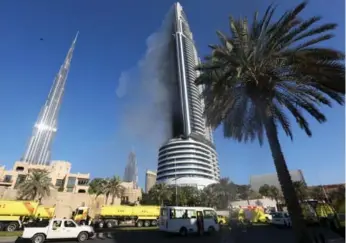  ?? REUTERS ?? Plumes of smoke billow from the Address Downtown Dubai hotel and residentia­l block near the Burj Khalifa, the tallest building in the world, a day after the Address caught fire.