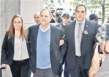  ?? — AFP file photo ?? Weinstein (centre) arrives for arraignmen­t at Manhattan Criminal Courthouse in handcuffs after being arrested and processed on charges of rape, committing a criminal sex act, sexual abuse and sexual misconduct last week in New York City.