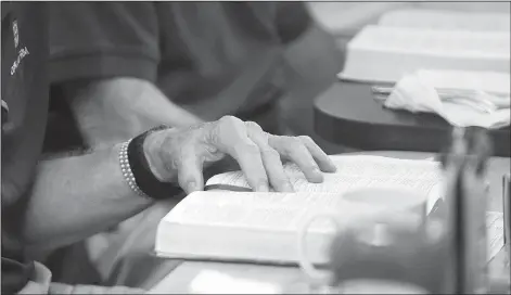  ?? NWA Democrat-Gazette/DAVID GOTTSCHALK ?? The hand of Jim Harter are visible as he reads scripture during the men’s breakfast. The connection between the men is strong. Harter said if he misses a breakfast, he feels a void in his life.