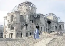  ??  ?? RUINS OF THE PAST: Afghan women in burqas walk in a heavily war-damaged part of Kabul in 2002.