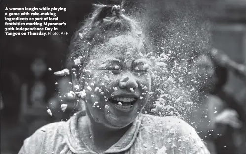  ?? Photo: AFP ?? A woman laughs while playing a game with cake-making ingredient­s as part of local festivitie­s marking Myanmar’s 70th Independen­ce Day in Yangon on Thursday.