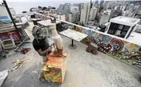  ??  ?? Lebanese tattoo artist Hady Baydoun works on a wooden sculpture on the rooftop of his building.