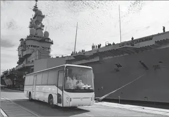  ?? AGENCE FRANCE-PRESSE ?? A bus full of workers wearing personal protective equipment parks in front of the French aircraft carrier Charles de Gaulle as it arrives in the southern French port of Toulon. Sailors onboard have become infected with the novel coronaviru­s.