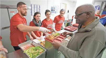  ?? PHOTOS BY MIKE DE SISTI / MILWAUKEE JOURNAL SENTINEL ?? Veteran Matt McDonell (left) serves a meal Sunday to Air Force veteran James Bradford at VETS Place Central as volunteers Allison Amateis (second left), her sister, Stephanie Amateis, and their father, Marc Amateis, look on. See more photos at...