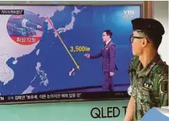  ??  ?? SEORANG askar Korea Selatan berjalan melintasi skrin televisyen yang menunjukka­n grafik jarak antara Korea Utara dan Guam di sebuah stesen kereta api di Seoul, semalam. - AFP