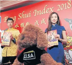  ?? REUTERS ?? ‘Sorcerer’s apprentice’ Sally Chan, right, and ‘wand bearer’ Alec So from CLSA pose with the Feng Shui Index report for Year of the Dog in Hong Kong yesterday.
