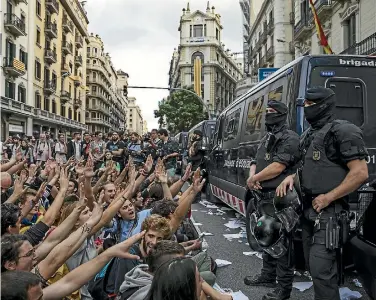  ?? PHOTO: REUTERS ?? Catalonian police officers surround the offices of the Spanish National police in Barcelona as protesters gather outside yesterday following the disputed independen­ce referendum.