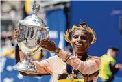  ?? Steven Senne/Associated Press ?? Hellen Obiri, of Kenya, displays the trophy on finish line after winning the women’s division at the Boston Marathon on Monday.