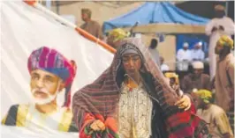  ??  ?? Members of a dance troupe, in traditiona­l garb, wait to perform next to a giant sail adorned with a portrait of the Sultan of Oman, Qaboos al-said, during a festival celebratin­g the monsoon season, in Salalah, Oman. The 60-day festival features dance...