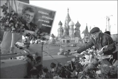  ?? AP/PAVEL GOLOVKIN ?? People lay flowers Saturday at the spot in Moscow where Russian opposition leader Boris Nemtsov was gunned down a year ago. The poster at the memorial site says, “The destiny of the country is dearer than life.”