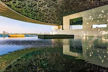 ??  ?? Louvre Abu Dhabi Die flach gewölbte Kuppel und die Fassade des Gebäudes spiegeln sich im Wasser. Das Bild wird links oben und unten an den Ecken gefasst und entwickelt sich in „Leserichtu­ng”. (Jean Nouvel, Paris, 2017)