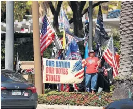  ?? STEPHEN M DOWEL/ ORLANDO SENTINEL ?? Demonstrat­ors wave flags at passing traffic outside the CPAC gathering at the Hyatt Regency in Orlando on Saturday.