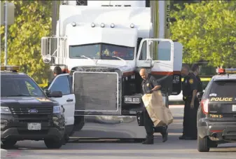  ?? Eric Gay / Associated Press ?? San Antonio police officers investigat­e the scene where at least nine people died after riding in a tractor-trailer loaded with as many as 100 others in stifling heat. The driver was arrested.