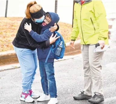  ?? JEFFREY F. BILL/CAPITAL GAZETTE ?? A hug goodbye from Mom as Brooklyn Park Elementary students arrive for the first day of hybrid learning in Anne Arundel County on March 1.