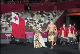  ?? DOUG MILLS — THE NEW YORK TIMES ?? Flag bearers Pita Taufatofua, center, and Malia Paseka, left, lead the team from Tonga during the opening ceremony of the Tokyo Olympics in July. Taufatofua has raised hundreds of thousands of dollars to help Tonga’s relief efforts following the volcanic eruption and tsunami this month.