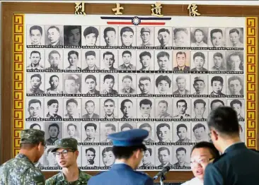  ?? — AFP ?? Fallen comrades: Military personnel talking in front of portraits of deceased soldiers during the 60th anniversar­y of the ‘823 bombardmen­t’ in Kinmen.