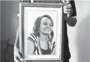  ?? — Gambar AFP ?? TINGGAL KENANGAN: Seorang anggota keluarga Mwatha mempamerka­n potretnya yang berbingka di rumahnya di Dandora, pinggir Nairobi pada Khamis lepas.