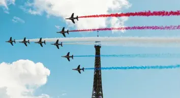  ?? Foto: Gao Jing, dpa ?? Die Kunstflugs­taffel der französisc­hen Luftwaffe fliegt am Eiffelturm vorbei und hinterläss­t Kondensstr­eifen in den Farben der Nationalfl­agge. Kaum eine Stadt dürfte geeigneter sein, die kommenden Sommerspie­le auszuricht­en.