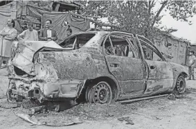  ?? KHWAJA TAWFIQ SEDIQI/AP ?? People gather around a vehicle from which rockets were fired in Kabul, Afghanista­n, on Monday. A neighborho­od near the airport was hit.