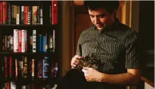  ?? Michael Ciaglo / Houston Chronicle ?? Joshua Zinn pets his cat at his Galleriaar­ea apartment, where he lives alone like 32 percent of people in Houston.