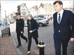  ?? AP PHOTO ?? Britain’s Prime Minister Theresa May, centre, is accompanie­d by members of the police as she views the area where former Russian double agent Sergei Skripal and his daughter were found critically ill, in Salisbury, England, Thursday.