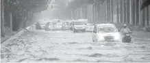  ??  ?? Motorists try to negotiate a flooded street in Manila today.