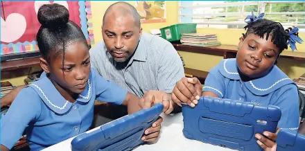  ??  ?? In this 2015 photo, Julian Robinson, then minister of state in the Ministry of Science, Technology, Energy and Mining, is showing Lumaya Fuller (left) and Leonie Facey how to do coding at the Clan Carthy Primary School.