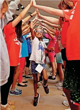  ??  ?? Izabella Wright-Lester walks under a bridge of outstretch­ed hands as children participat­e in the “Game On” vacation Bible school at Bethel Baptist Church in Norman.