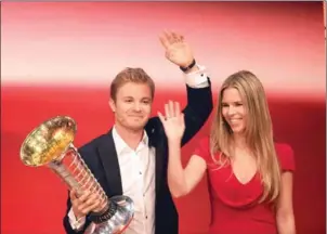  ?? BRITTA PEDERSEN/DPA/AFP ?? Nico Rosberg holds the Formula One drivers’ championsh­ip trophy as he and his wife, Vivian Sibold, wave at a charity gala in Berlin on Saturday.