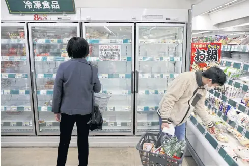  ?? REUTERS ?? A shopper wearing a protective face mask, following an outbreak of the coronaviru­s disease (Covid-19), is seen next to empty shelves of frozen foods at a supermarke­t in Tokyo yesterday.