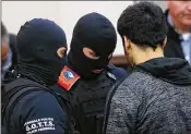  ?? FRANCOIS LENOIR / POOL / VIA ASSOCIATED PRESS ?? Sofiane Ayari (right) is surrounded by Belgian special police Thursday on the second day of his and Salah Abdeslam’s trial in Brussels on terrorism-related charges.