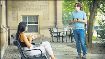  ?? JASON KOSKI — CORNELL UNIVERSITY VIA AP ?? In this photo provided by Jason Koski and Cornell University, Bryan Maley, right, a grad student in the Master of Public Health program, interviews a student on campus about mask-wearing experience­s as part of a public health survey, Friday, July 30, 2020, in Ithaca, N.Y.