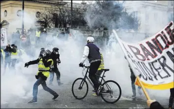  ?? Kamil Zihnioglu The Associated Press ?? Demonstrat­ors stand in tear gas thrown by riot police during a protest in Paris on Saturday. Protests were held in Paris and other French cities.