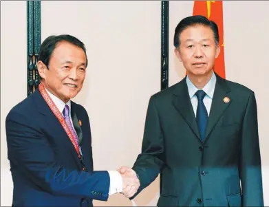  ?? MA PING / XINHUA ?? Finance Minister Xiao Jie (right) shakes hands with his Japanese counterpar­t, Taro Aso, during the Sixth China-Japan Finance Dialogue in Yokohama, Japan, on Saturday.